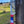 Load image into Gallery viewer, A stainless steel comb with 'STEELTOOTH' etched at the top, suspended on a weathered wooden post by red, white, and blue hemp cord wrapped around the handle. The comb is set against a soft-focus background of a peaceful countryside scene.