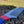 Load image into Gallery viewer, A sleek stainless steel comb lies atop a rugged, textured surface, with a red, white, and blue hemp cord wrapped around the handle. The comb is sharply in focus against a blurred natural landscape in the background, embodying a blend of ruggedness and patriotic elegance.