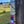 Load image into Gallery viewer, A stainless steel comb with &#39;STEELTOOTH&#39; etched at the top, suspended on a weathered wooden post by red, white, and blue hemp cord wrapped around the handle. The comb is set against a soft-focus background of a peaceful countryside scene.
