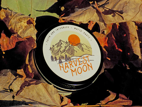 Faith and Integrity Harvest Moon matte paste sitting in a bed of fall leaves. Used for matte and texturized hairstyles. 