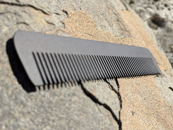A steeltooth new standard comb with a deep red/brown finish on it on a rock.  